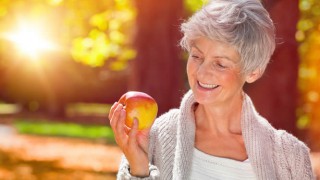 Eine ältere Frau hält einen Apfel in der Hand