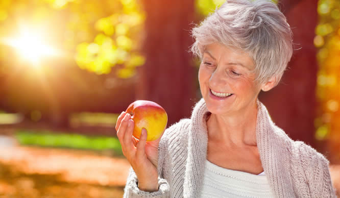 Eine ältere Frau hält einen Apfel in der Hand