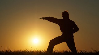 Ein Mann macht im Sonnenuntergang Kung Fu-Übungen