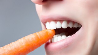 Der Mund einer Frau beim Biss in eine Karotte