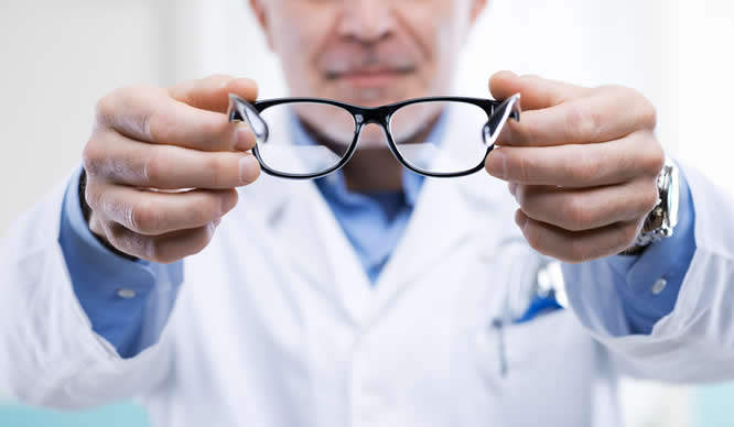 Ein Augenarzt reicht seinem Patienten eine Brille