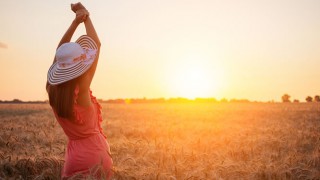 Eine Frau genießt den Sonnenuntergang in einem Kornfeld