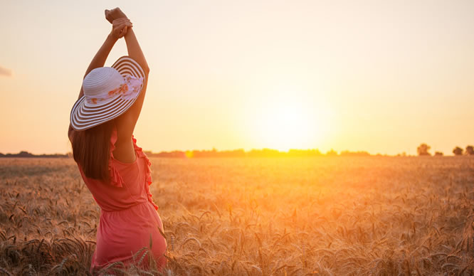 Eine Frau genießt den Sonnenuntergang in einem Kornfeld