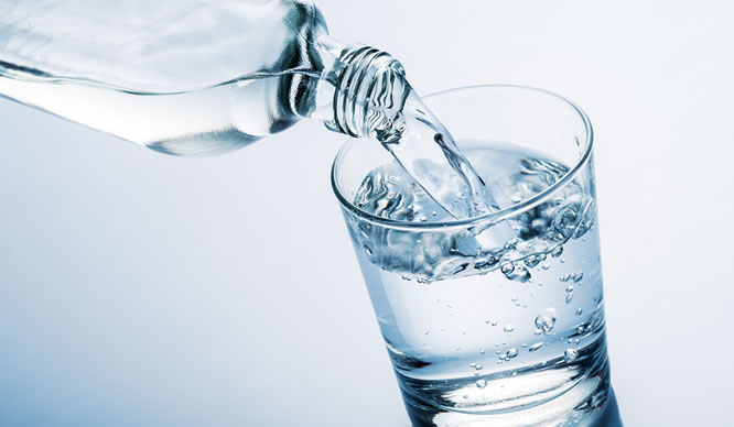 Wasser wird aus einer Flasche in ein Glas gegossen