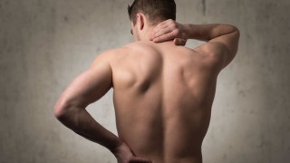 Ein Mann mit Muskelkater massiert sich den Nacken