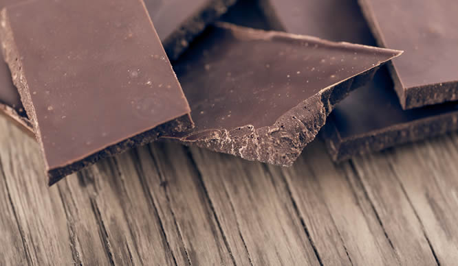 Dunkle Schokoladenstücke auf einem Holzbrett