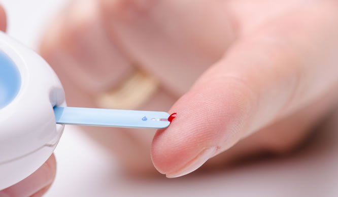 Der Blutzuckerspiegel wird über einem Blutstropfen am Finger gemessen