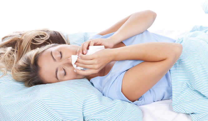 Eine Frau im Bett leidet an Hausstaub-Allergie