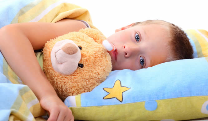 Ein kleiner Junge liegt mit Fieber im Bett