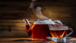Eine dampfende Teekanne mit einer Tasse