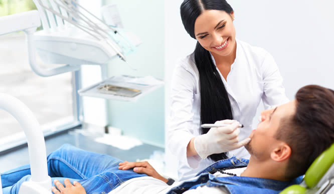 Eine attraktive Zahnärztin behandelt einen Patienten