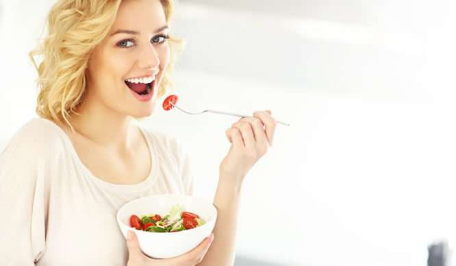 Eine junge Blondine isst einen Salat