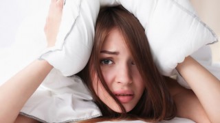 Eine junge Frau liegt wach im Bett
